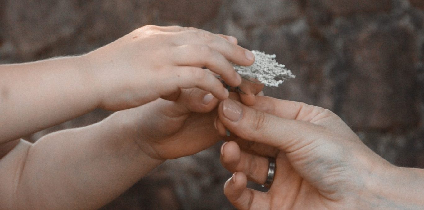 Kinderhand mit Blume für Mama